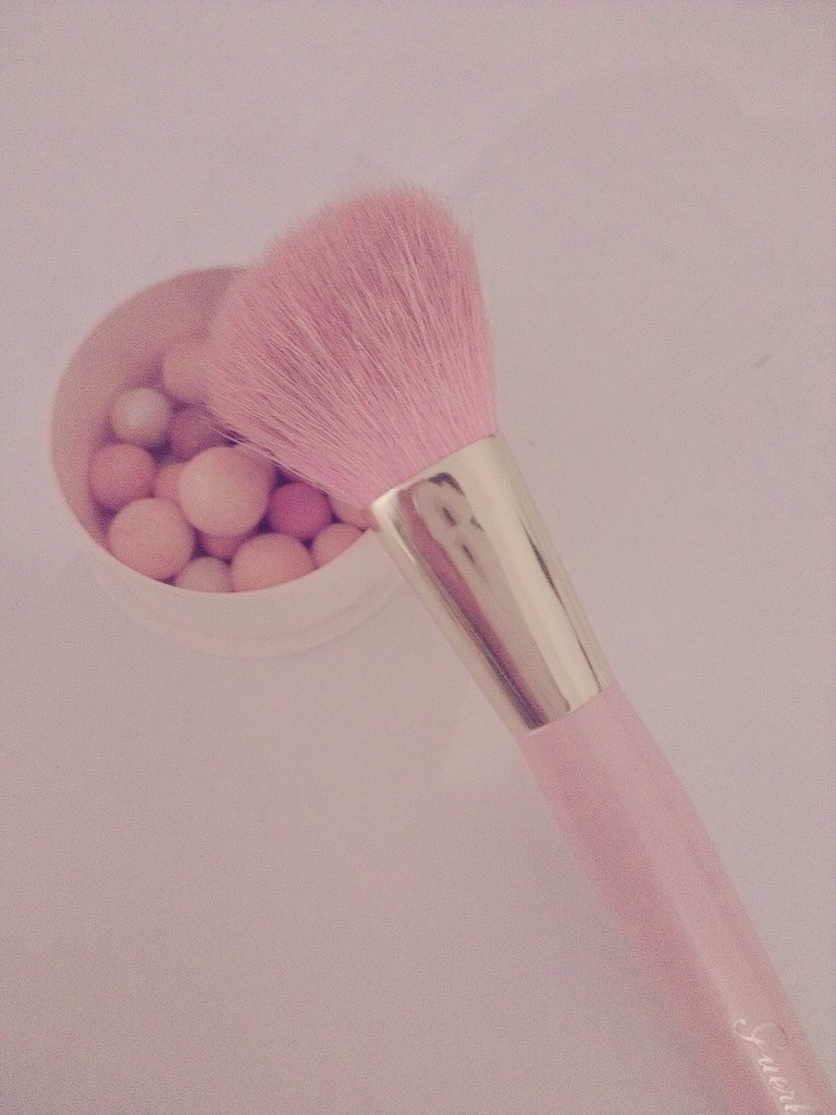 Pink makeup brush with blush and highlighter